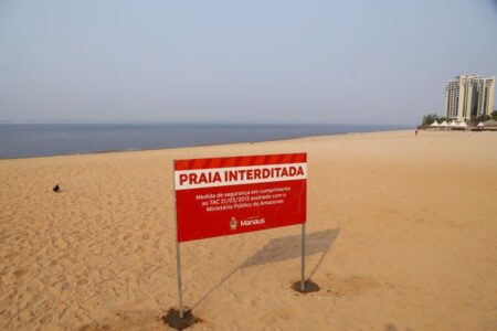 A praia do complexo turístico Ponta Negra, na zona Oeste, segue interditada para o banho por conta da severa estiagem na capital e no Estado do Amazonas. A cota do rio Negro está na marca de 16,34 metros, nesta quinta-feira, 19/12. A interdição foi decretada pela Prefeitura de Manaus, incluindo o período das festividades de fim de ano. Para o Réveillon da cidade, tradicional evento que já acontece no complexo e na praia, a interdição permanece sem alteração, se somando às orientações de segurança, definidas pelo Centro de Cooperação da Cidade (CCC), para montagem do palco e estrutura, para receber as comemorações da virada de ano. A decisão de interditar a praia para o banho, em razão de segurança e de prevenção contra afogamentos, ocorre devido à proximidade entre o fim do aterro perene e o leito natural do rio, que pode apresentar alterações no terreno, como buracos, desníveis, depressões e, até mesmo, o surgimento de banco de areias. A Prefeitura de Manaus orienta que os banhistas não entrem no rio. As placas de interdição seguem no local, em diversos pontos da faixa de areia e nos acessos. Proibições Em grandes eventos, como o Réveillon, o corpo de segurança permanente do complexo proíbe a entrada de materiais cortantes e/ou perfuro-cortantes, bem como perfuro-contundentes, como armas de fogo, brancas ou de arremesso, além de garrafas, pratos, copos de vidro ou alumínio, latas, fogos de artifício, animais, embalagens de spray, substâncias inflamáveis, hastes de bandeiras, guarda-chuvas, dardos, martelos, seringas, extintores, capacetes ou quaisquer objetos que ameacem a integridade física dos presentes. Interdição A interdição considera as normas de uso da praia perene, definidas em um Termo de Ajustamento de Conduta (TAC) assinado pela Prefeitura de Manaus junto ao Ministério Público do Estado do Amazonas (MP-AM), com órgãos municipais e estaduais signatários do compromisso, incluindo o Corpo de Bombeiros do Amazonas e a Polícia Militar.