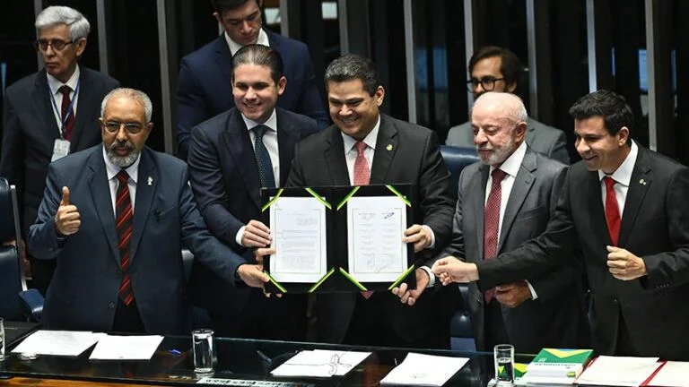 O presidente da República, Luiz Inácio Lula da Silva, participou, nesta sexta-feira (16/10), no Plenário do Senado Federal, da sessão solene do Congresso Nacional realizada para promulgar duas emendas à Constituição: a que trata do fim da escala de trabalho 6x1, prevista na PEC 221/2019, aprovada no Senado na quarta-feira (14/10); e a decorrente da PEC 14/2021, que prevê aposentadoria especial para agentes comunitários de saúde. Uma das pautas prioritárias para o Governo Federal, o fim da escala de trabalho 6x1 assegurará série de avanços e impactará a vida de quase 15 milhões de trabalhadores. A iniciativa reduz o limite da jornada de 44 para 40 horas semanais, assegura ao trabalhador dois dias de descanso remunerado e proíbe qualquer redução salarial. Em 13 de abril deste ano, o presidente assinou mensagem que formalizou o envio ao Congresso Nacional de projeto de lei sobre o tema. A pauta buscava garantir mais tempo para a família, lazer, cultura, estudo e descanso, com reflexos positivos na produtividade. A proposta recebeu 75 votos favoráveis e um contrário nos dois turnos de votação no Senado. Na Câmara dos Deputados, a PEC foi igualmente aprovada por ampla maioria. DIA HISTÓRICO – Ao classificar a sessão solene como um dia histórico para o trabalhador brasileiro, o presidente Lula ressaltou que a promulgação do fim da escala 6x1 e da aposentadoria especial para agentes comunitários de saúde mostram que a democracia vale a pena. Segundo o presidente da República, as emendas incluíram páginas importantes na Constituição Federal. Para ele, a Carta Magna agora está mais cidadã, mais defensora da sociedade e estabelece mais dignidade para o povo brasileiro. O presidente do Senado e do Congresso Nacional, Davi Alcolumbre, ao ressaltar que ter mais tempo de descanso, mais tempo com a família, mais tempo para cuidar de si e de quem se ama são avanços que não têm preço, afirmou que as duas emendas representam conquistas enormes para milhões de trabalhadores e trabalhadoras brasileiras. O parlamentar agradeceu aos senadores e deputados que ajudaram a construir ambas as emendas à Constituição promulgadas nesta sexta-feira (16/10). Já o presidente da Câmara dos Deputados, Hugo Motta, frisou que a solenidade transforma duas lutas históricas em direitos. Ele afirmou que as emendas, apesar de tratarem de conquistas distintas, estão unidas pelo mesmo princípio: o de que o trabalho merece dignidade e o de que quem trabalha merece qualidade de vida. BENEFICIADOS – Trabalhadores de diferentes setores econômicos, especialmente nas áreas de comércio, serviços, indústria e logística, serão alcançados pela redução da jornada semanal. Levantamento do Ministério do Trabalho e Emprego identificou a jornada de trabalho de 44,7 milhões de pessoas no Brasil. Do total, cerca de um terço trabalha no regime 6x1, o equivalente a 14,9 milhões de trabalhadores que seriam beneficiados pela mudança para o modelo 5x2. Os dados também apontam que 38,6 milhões de trabalhadores informaram cumprir jornadas superiores a 40 horas semanais. Destes, 37,2 milhões trabalham 44 horas semanais, e 1,4 milhão trabalham entre 40,1 e 43,9 horas semanais. ESTADOS E REGIÕES — O Sudeste concentra o maior contingente de trabalhadores na escala 6x1, com 7 milhões de pessoas. Na sequência aparecem Sul (2,9 milhões), Nordeste (1,97 milhão), Centro-Oeste (1,34 milhão) e Norte (751,7 mil). Entre os estados, São Paulo possui o maior número de trabalhadores na escala 6x1, com 4,28 milhões de pessoas. Na sequência aparecem Minas Gerais (1,46 milhão), Rio de Janeiro (1,05 milhão), Santa Catarina (1,04 milhão) e Paraná (1,03 milhão). MAIS JUSTIÇA SOCIAL – Ao assegurar mais tempo livre para o trabalhador, o fim da escala 6x1 visa melhorar a qualidade de vida, fortalecer a convivência familiar e reduzir impactos na saúde. Em 2024, o país registrou cerca de 500 mil afastamentos por doenças psicossociais relacionadas ao trabalho. Um estudo do Instituto de Pesquisa Econômicas Aplicadas (Ipea) indica que as jornadas de trabalho mais longas, de 44 horas semanais, se concentram entre trabalhadores de menor renda e escolaridade. O levantamento mostra que a redução para 40 horas elevaria o custo médio do trabalho em apenas 7,84%. Essa transição é vista como medida concreta de justiça social, com potencial para aumentar a produtividade, reduzir afastamentos por saúde e dinamizar o consumo no comércio local. TRANSIÇÃO – A transição do fim da escala 6x1 ocorrerá em duas etapas. Dois meses após a publicação da emenda no Diário Oficial da União (DOU), a jornada máxima cai de 44 horas para 42 horas semanais. E os trabalhadores passam a ter direito a dois dias de descanso remunerado por semana, sendo um deles preferencialmente aos domingos. Um ano e dois meses depois da publicação no DOU (14 meses), chega, definitivamente, a 40 horas. Durante a transição, acordo ou convenção coletiva pode ampliar a jornada diária para acomodar as 42 horas semanais, desde que mantidos os dois dias de repouso. E podem instituir compensação do repouso, desde que a média mensal garanta dois dias de folga por semana, com ao menos um dia a cada sete. ACORDOS COLETIVOS – Cláusulas de acordos coletivos incompatíveis com as novas regras perdem validade dois meses após a publicação da emenda. A entrada em vigor da mudança não implicará redução proporcional das jornadas já fixadas em patamar igual ou inferior a 40 horas semanais. Lei complementar poderá prever transição para MEIs, microempresas e pequenas empresas, condicionadas à manutenção do nível de emprego. REGRAS ESPECIAIS – As novas regras de duração e controle de jornada não valem para empregados com diploma superior que recebam ao menos 2,5 vezes o teto do Regime Geral de Previdência Social (RGPS) — salvo por liberalidade do empregador ou previsão em acordo coletivo —, mantidas as regras de repouso. Também não se aplicam a servidores públicos de nenhum dos Poderes da União, dos estados, do Distrito Federal e dos municípios, cabendo à Justiça do Trabalho julgar disputas sobre o tema. Em contratos vigentes da administração pública que envolvam mão de obra (inclusive concessões de serviços e obras), a redução de jornada vale após aditamento contratual — a ser formalizado em até um ano —, para preservar o equilíbrio econômico. Já o segundo dia de repouso independe de aditamento e passa a valer dois meses após a publicação da emenda. Trabalhadores nesses contratos passam a ter jornada reduzida na data do aditamento ou, no limite, ao fim de um ano, com garantia de irredutibilidade salarial. O QUE MUDA NA PRÁTICA COM O FIM DA JORNADA 6X1 ● Jornada semanal: limite passa de 44 para 40 horas ● Descanso ampliado: ao menos dois dias de repouso semanal remunerado ● Novo padrão: consolidação do modelo 5x2 e redução das horas trabalhadas ● Salário protegido: vedada qualquer redução salarial ● Abrangência ampla: inclui domésticos, comerciários, atletas, aeronautas, radialistas e outras categorias abrangidas pela CLT e leis especiais ● Aplicação geral: limite de 40 horas passa a valer também para escalas especiais e regimes diferenciados ● Flexibilidade: mantém escalas como 12hx36 por acordo coletivo, respeitada a média de 40 horas por semana AVANÇO TECNOLÓGICO – Experiências internacionais mostram que, quando implementada com planejamento e diálogo, a redução da jornada contribui para melhor organização do trabalho e ganhos de produtividade. Além disso, a mudança dialoga com transformações recentes na economia, como o avanço tecnológico. O projeto aproxima o Brasil de um movimento já em curso em diversos países. O Chile aprovou a redução gradual da jornada de 45 para 40 horas semanais até 2029, enquanto a Colômbia está em transição de 48 para 42 horas até 2026. Na Europa, a jornada de 40 horas ou menos já é predominante: a França adota 35 horas semanais desde os anos 2000, e países como Alemanha e Holanda operam, na prática, com médias inferiores a 40 horas. AGENTES DE SAÚDE – Além do fim da jornada 6x1, a solenidade promulgou a Emenda à Constituição que cria a aposentadoria especial de agentes comunitários de saúde e agentes de combate às endemias. O texto aprovado fixa regras permanentes e transitórias de aposentadoria para as duas categorias; disciplina a contratação desses agentes; estende as regras aos agentes indígenas de saneamento e de saúde; e indica a forma como a União custeará o aumento de despesa. Com a aprovação da PEC A idade mínima para a aposentadoria da categoria será de 57 anos para as mulheres e de 60 anos para os homens, desde que comprovados 25 anos de contribuição e de efetivo exercício na atividade profissional. O texto garante integralidade da aposentadoria do servidor que tenha ingressado no serviço público até a data de promulgação da emenda constitucional. E, também, paridade do reajuste da aposentadoria com a remuneração dos servidores em atividade. Atualmente, a aposentadoria dessas categorias segue a regra geral: no mínimo 62 anos de idade para mulheres e 65 para homens, com pelo menos 15 anos de contribuição no caso do Regime Geral de Previdência Social (RGPS) e 25 anos de contribuição no caso do Regime Próprio de Previdência Social (RPPS).